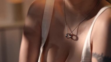 Hassas bir dokunuşla boynunu ve göğsünü okşayan şefkatli bir kadın. Güzel güneş ışığıyla yakın çekim. Tenine zarif gölgeler düşüyor.