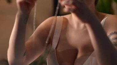 Gümüş bir kolye takan dövmeli genç bir kadının yakın çekimi. Güzel bir sabah güneşi altında içeride duruyor, hazırlanıyor.