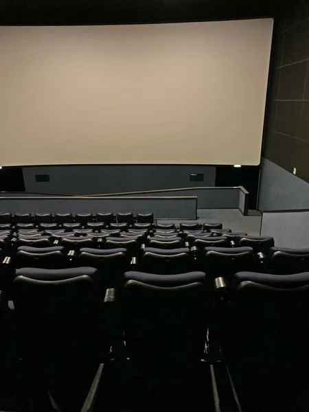 Empty cinema auditorium with empty white screen.