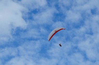 Bir paraglider üzerinde uçmak. Mavi gökyüzünün arka planında iki yolcusu olan paraglider 
