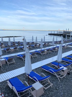 Denizin ilk sırasındaki güneş yatakları ve şemsiyeler. Otel plajı. 