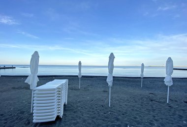 Çakıl taşı plajında kapalı plaj şemsiyeleri. Sabahın köründe deniz sahilinde. Kimse yok. 