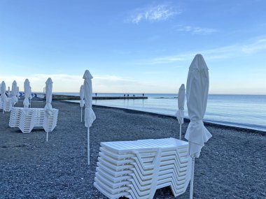 Çakıl taşı plajında kapalı plaj şemsiyeleri. Sabahın köründe deniz sahilinde. Kimse yok. 