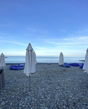 Çakıl taşı plajında kapalı plaj şemsiyeleri. Sabahın köründe deniz sahilinde. Kimse yok. 