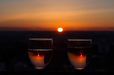 Günbatımı arka planında beyaz şarap olan iki bardak, akşam güneşi sisli bir bardağa yansıyor. Kutlama kavramı, romantik randevu kokteyli, aşk randevusu.