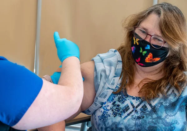 a health care worker prepares to administer a covid moderna jab to an older woman at a health care clinic