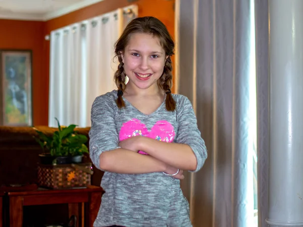 一个戴着辫子的小女孩在家里的一个家庭房间里摆姿势 — 图库照片