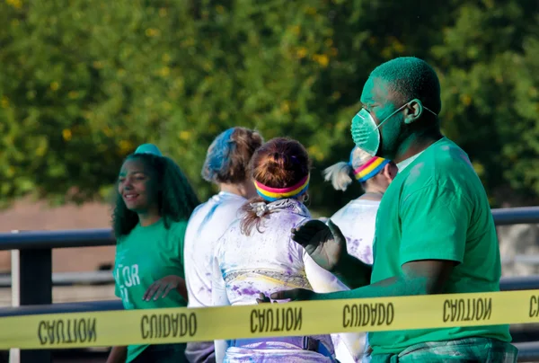 Trabalhador verde em uma corrida de cor com máscara — Fotografia de Stock