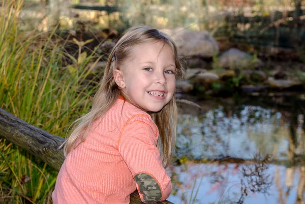 Menina por uma pequena lagoa no jardim — Fotografia de Stock