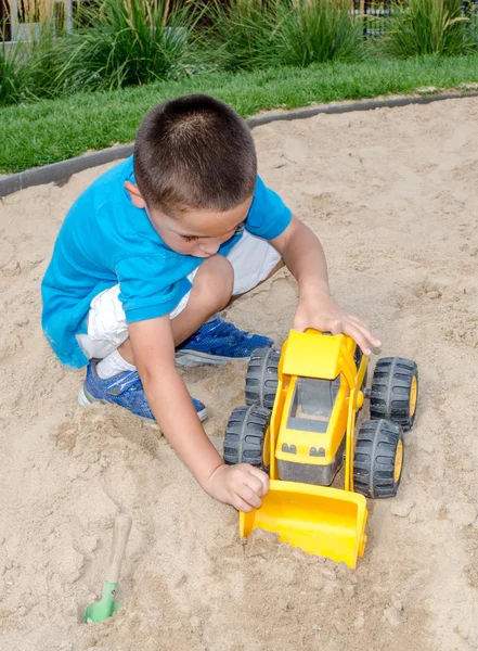 Niño jugando en la arena con el cargador frontal de juguete —  Fotos de Stock