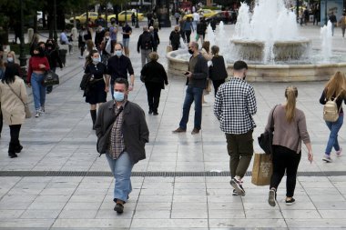 Korunaklı yüz maskeleri takan insanlar, 3 Kasım 2020 'de Atina, Yunanistan' da, koronavirüs hastalığı (COVID-19) salgını sırasında ticari bir sokakta yürüyorlar.