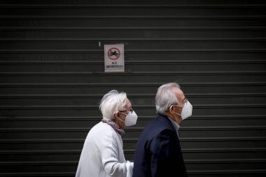 Korunaklı yüz maskeleri takan insanlar, 3 Kasım 2020 'de Atina, Yunanistan' da, koronavirüs hastalığı (COVID-19) salgını sırasında ticari bir sokakta yürüyorlar.