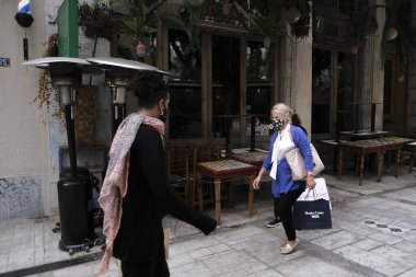 Yunanistan 'ın başkenti Atina' da 3 Kasım 2020 'de Covid-19 salgınının yayılmasına karşı yeni kısıtlayıcı tedbirlerin uygulanmasının ilk günü boyunca kapalı bir kafe önünde yürüyen bir yaya görülüyor.