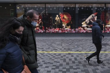 30 Kasım 2020 'de Brüksel, Belçika' da Noel için dekore edilmiş vitrinlere bakan yüz maskesi takan insanlar.