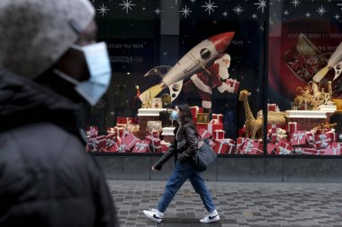 30 Kasım 2020 'de Brüksel, Belçika' da Noel için dekore edilmiş vitrinlere bakan yüz maskesi takan insanlar.