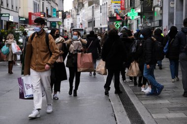 Yüz maskesi takan insanlar 1 Aralık 2020 'de Brüksel, Belçika' da yeniden açılan bir dükkanın önünden geçiyorlar..