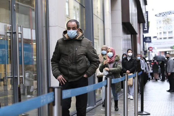 1 Aralık 2020 'de Brüksel' de, Neuve sokağındaki bir dükkanın önünde kuyruğa giren insanlar, yeni Coronavirus salgınının ortasında temel olmayan ürünler satan dükkanların yeniden açılmasına izin veriliyor.. 