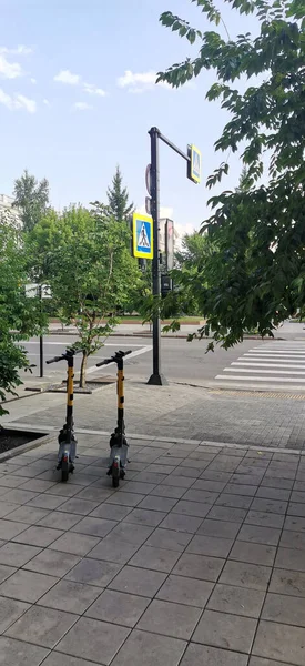 Ficklösa elektriska skotrar på trottoaren. Elektrisk skoter - prisvärd stadstransport. Bevarande av miljön, alternativa transporter. — Stockfoto