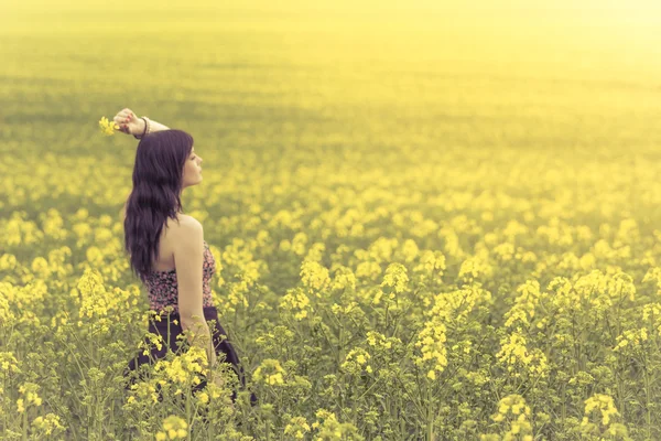 Beautiful woman in yellow flowers from side behind looking right. — Stock Photo, Image