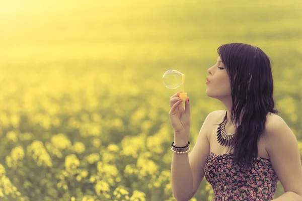 Beautiful woman blowing a single soap bubble in summer nature — Stock Photo, Image