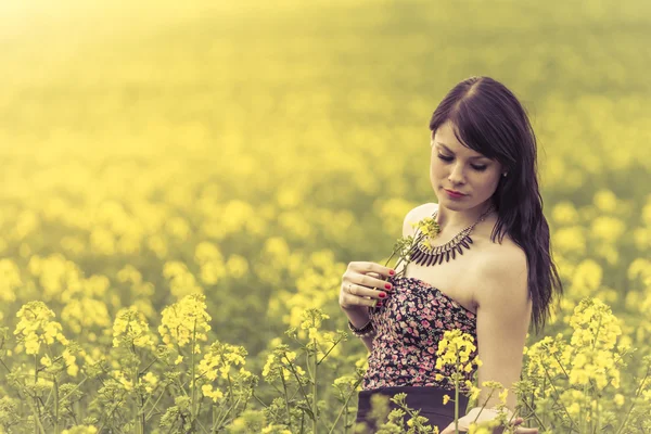 Krásná žena v louce žluté květy s glimps dolů — Stock fotografie