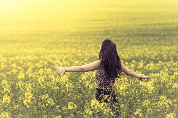 Vacker kvinna i ängen av gula blommor från bakom — Stockfoto