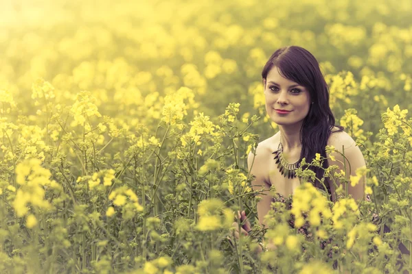 Belle femme dans la prairie de fleurs jaunes assis — Photo