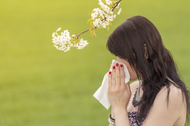 Beautiful hayfever girl wiping her nose in spring nature clipart