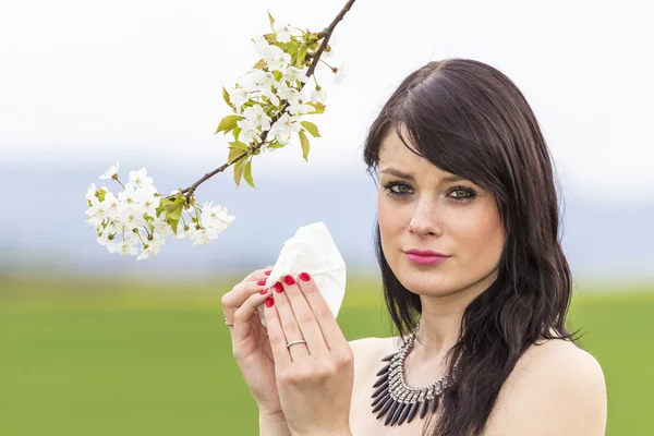 Sad hayfever girl in spring nature with blossom branch — Stock Photo, Image