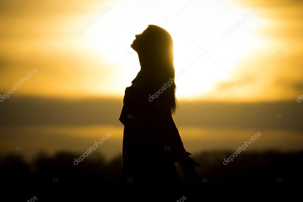 Twilight silhouette by beautiful sunny young woman in summer