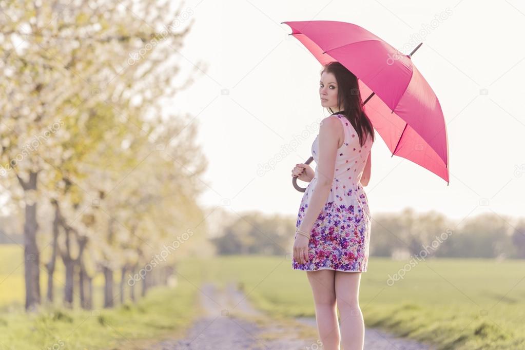 Beautiful young woman with red umbrella in spring or summer