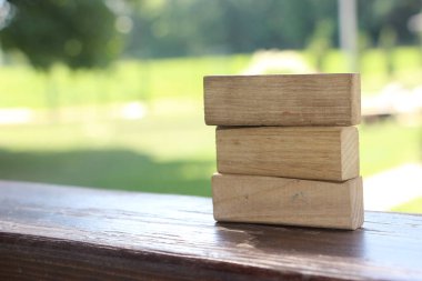 3 Ağaç Blok Ön Görünümü, Ahşap cilalı masa, yeşil doğa arka planda çözüldü.