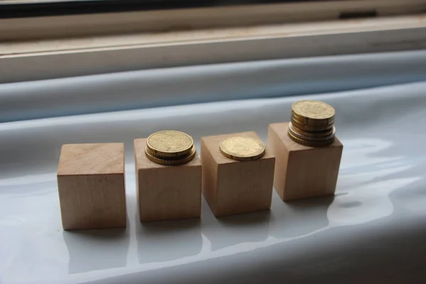 Wooden cubes with coins put into stacks. Business or personal savings investment concept.