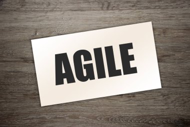 Kağıt kartvizitte AGILE yazılı, ahşap arka planda yakın plan. İş Konsepti