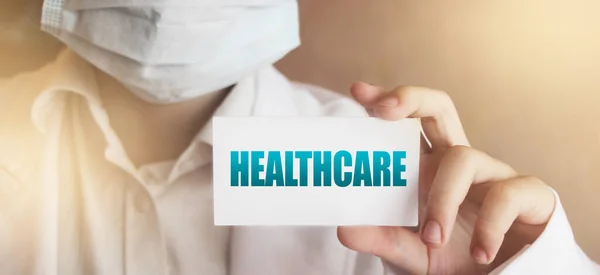 Healthcare word on the card in hands of Medical Doctor. Healthcare concept.