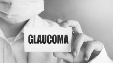 Glaucoma yazılı, hafif arka planda tıbbi giysiler giyen bir doktor. Seçici odaklanma. Tıbbi konsept.