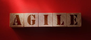 Ahşap küpler kırmızı arkaplanda çevik yazılıyor.