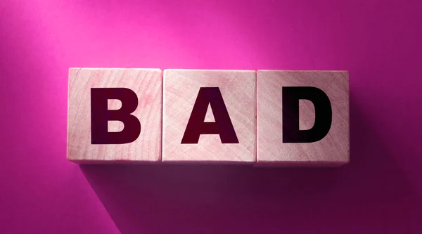 Bad word on wooden blocks on red background. Something negative concept top view.