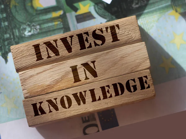 Blocchi di legno con iscrizione Investire nella conoscenza su sfondo da 100 Euro abills. Concetto di educazione aziendale — Foto Stock