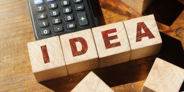 Masadaki tahta bloklar ve hesap makinesiyle parlak ışık kapanışında yapılmış bir kelime fikri. Girişim konsepti.