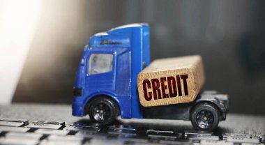 Tahta blokta kredi sözcüğü olan mukavva kutu ve keton arka planda mini forklift kamyonu. Lojistik ve Ulaştırma Yönetimi fikirleri ve Endüstri ticari konsepti.