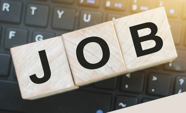 cubes with the word JOB in front of a keyboard. Computer related career concept.