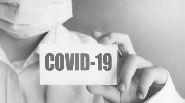 Doktor elinde COVID-19 yazılı bir kart tutuyor. Tıbbi sağlık konsepti..