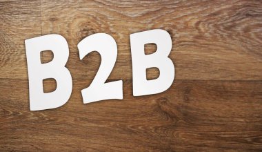 Tahta bir masanın üzerine B2B harfiyle yazılmış beyaz kağıttan kesilmiş harfler. İş İşe Kavram