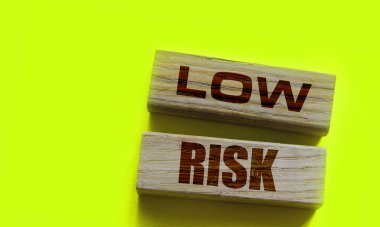 Düşük riskli kelimeler sarı üzerine tahta bloklar. İş yatırımları konsepti riske atıyor.
