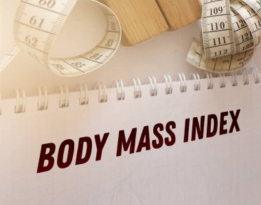 A white measuring tape and copybook with BMI body mass index words. Healthcare healthy living concept. clipart
