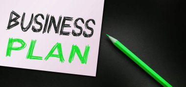 Kağıt ve turuncu kalemle yazılmış bir iş planı metni. İş konsepti.