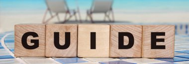 Rahat sahil manzarası üzerine tahta küplerle yazılmış Kelime Kılavuzu. Seyahat kavramı.