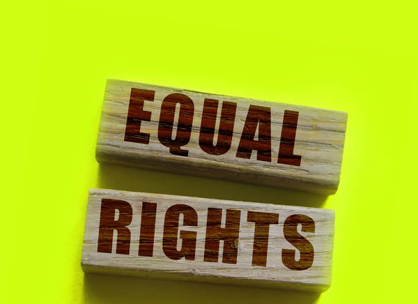 Equal rights words on wooden blocks on yellow background. Gender equality concept.