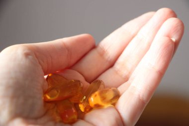 İlaç, besin takviyesi ve insan konsepti. Morina yağı kapsüllerini tutan ellere yakın. Omega-3 kapsüllerini tutan bir kadının elleri. Gıda takviyeleri ve sağlık konsepti.